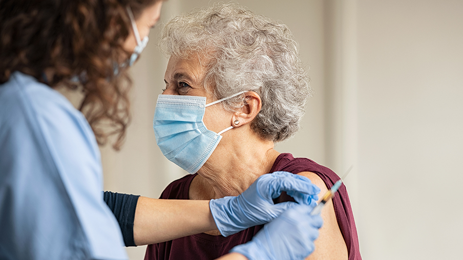 Enfermera de geriatría vacunando a señora mayor